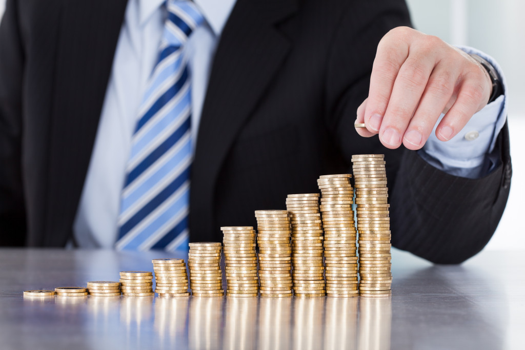 A businessman is placing another coin on a stack of coins