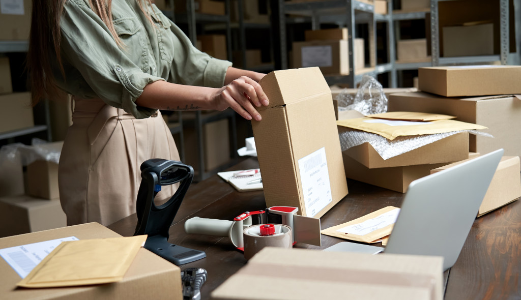 photo of a female business fixing a box for shipment for deliverywoman 