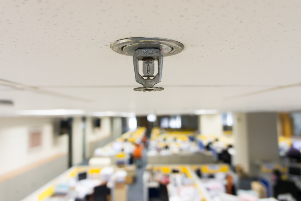 A close-up of a sprinkler nozzle on the ceiling of an office