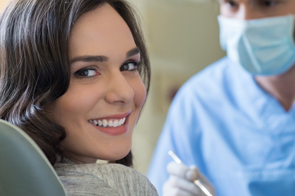 smiling woman with dentist checking her behind