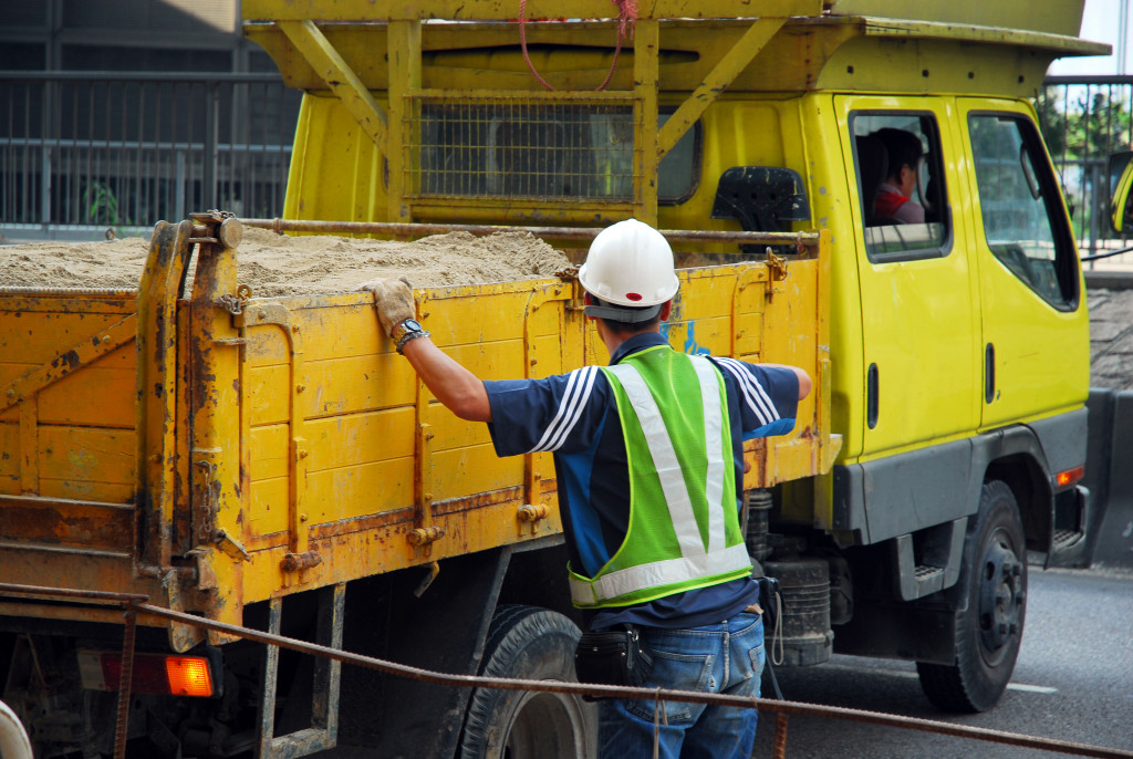 A construction worker guiding the driver of a dump truck park