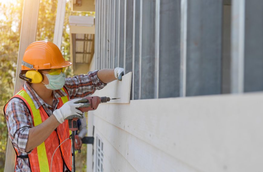 A construction worker drilling holes on a wood panel