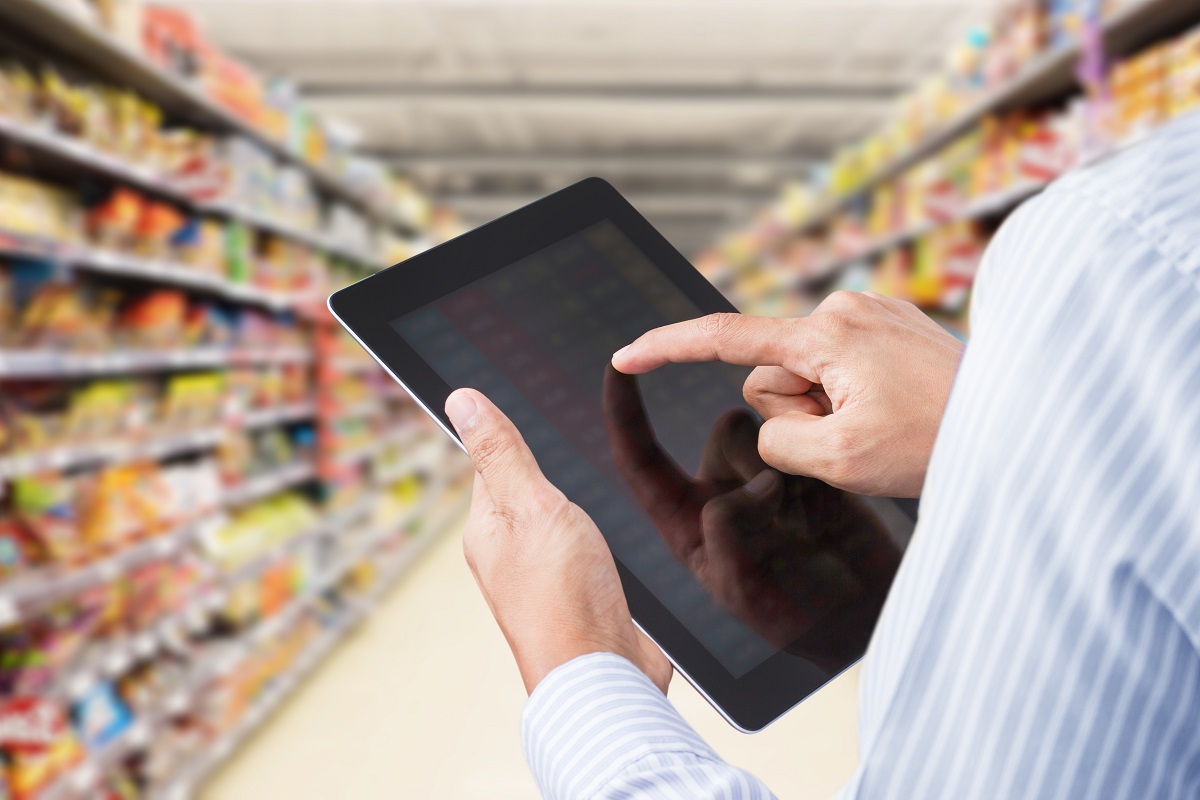 Business executive checking the sales and inventory at a grocery using a tablet.